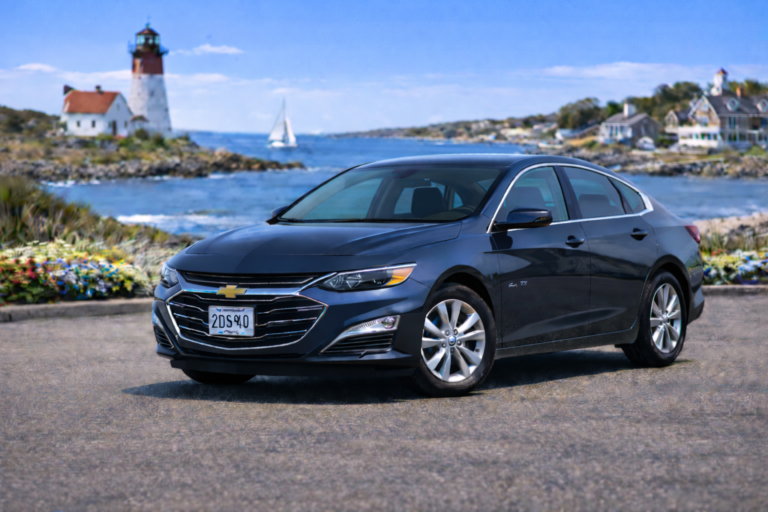 Dark blue Chevrolet Malibu rental from Vachon in Cranston, RI, shown with a lighthouse and coastal backdrop