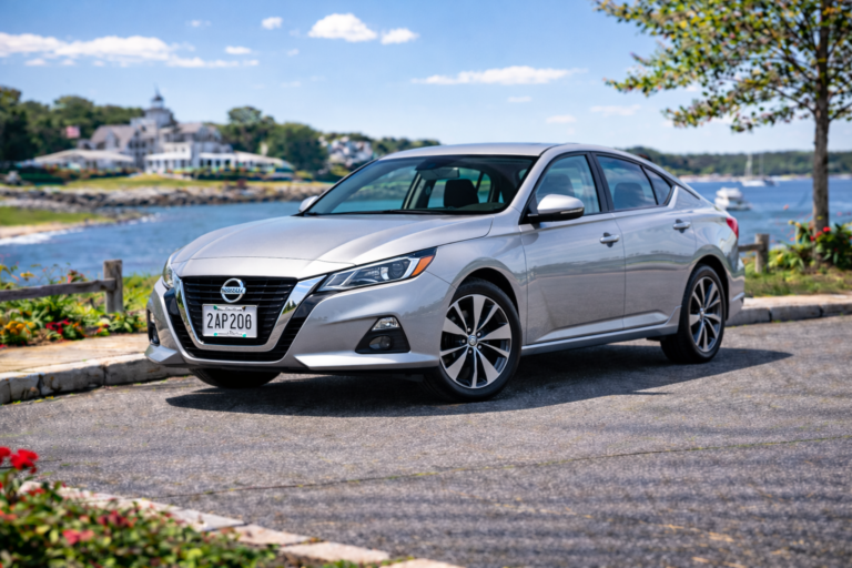 Silver Nissan Altima rental from Vachon in Cranston, RI, shown with a waterfront backdrop