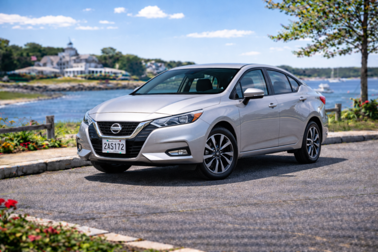 Silver Nissan Versa rental from Vachon in Cranston, RI, shown with a waterfront backdrop